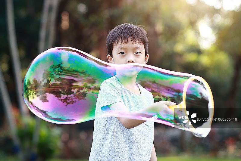 欢快的蹒跚学步的小男孩在公园里玩肥皂泡图片素材