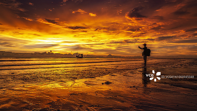 一位摄影师在海滩上拍摄日落剪影，快乐的假期概念在攀牙，泰国图片素材