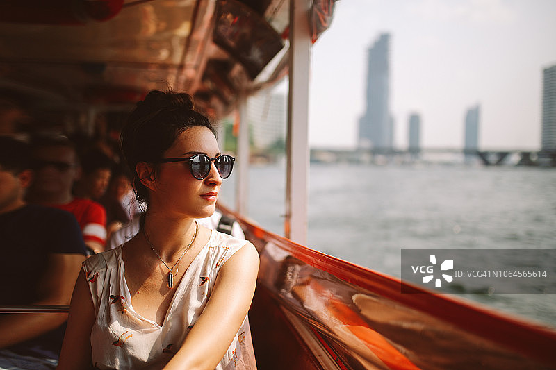 年轻的女游客坐在曼谷的渡船上图片素材