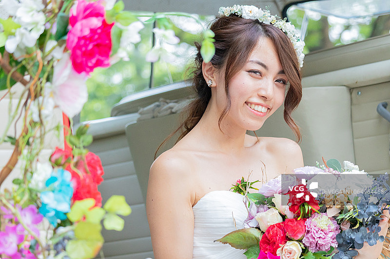 可爱的新娘微笑着，捧着花束在车里图片素材