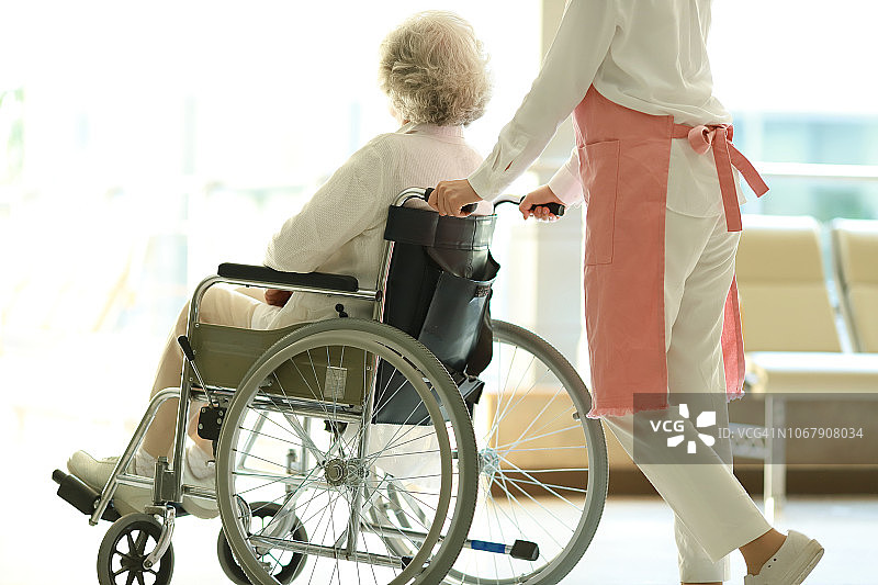 护工推着轮椅上的老妇人图片素材