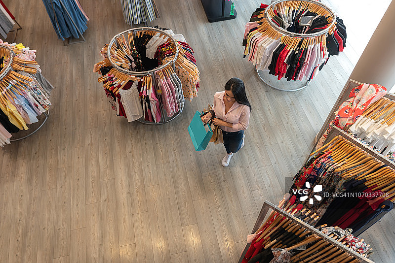 一位拉丁美洲妇女拿着购物袋在服装店走着图片素材