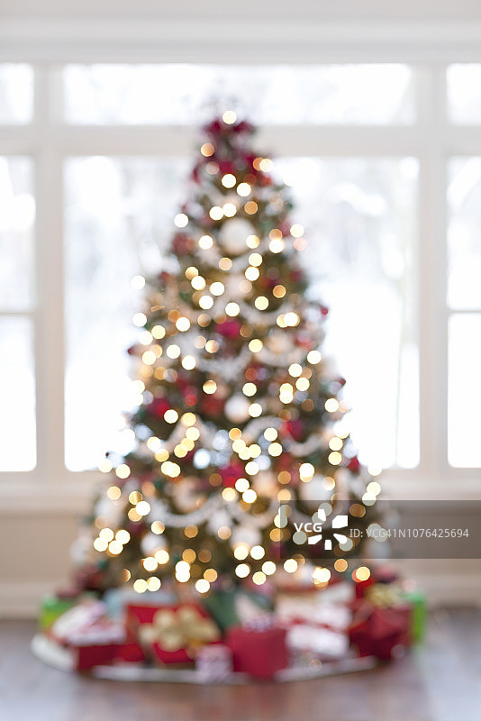 圣诞树与装饰物和礼物对着窗户图片素材
