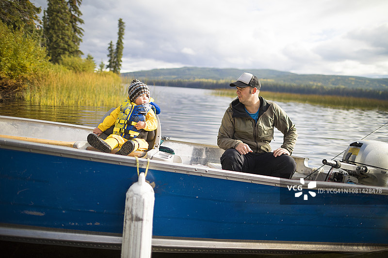 父亲和儿子坐在湖上的小船上图片素材