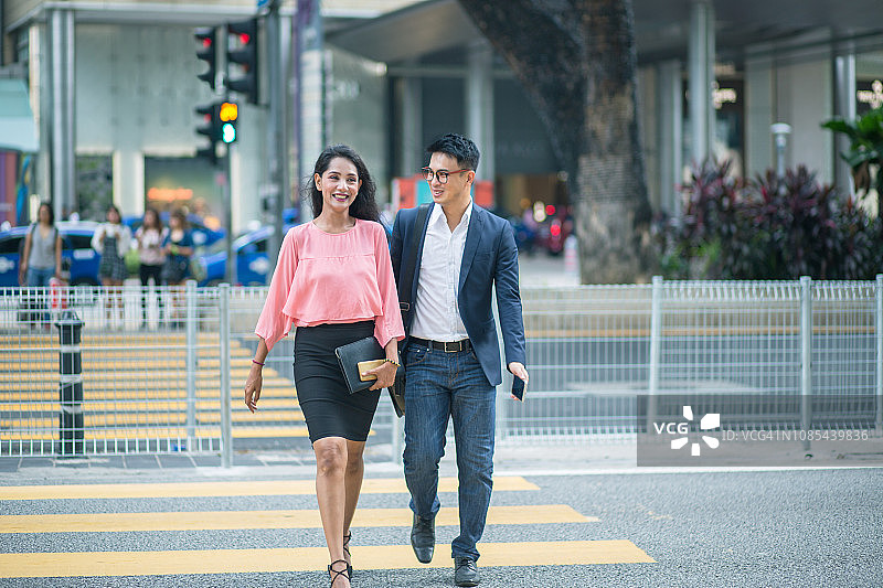 微笑的商业夫妇穿过步行区图片素材