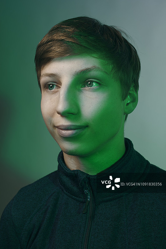 一个十几岁男孩的工作室肖像，用绿色的光照亮图片素材