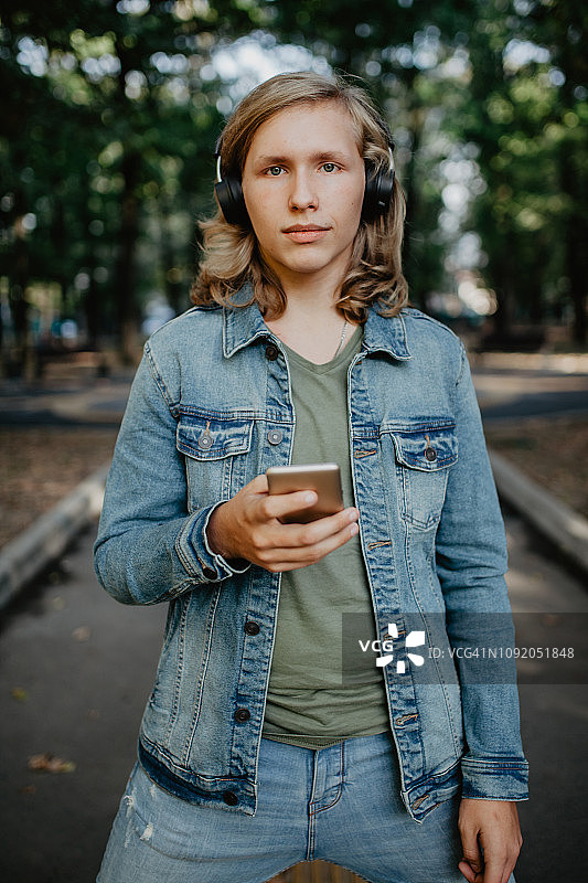 青少年用智能手机戴着无线耳机图片素材