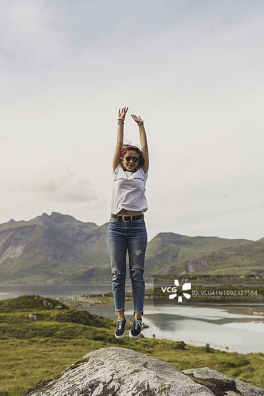 年轻女子在挪威拉普兰的一块岩石上跳图片素材