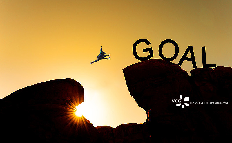 剪影一个人从悬崖上往目标跳。实现目标，商业目标，挑战和成功的概念图片素材
