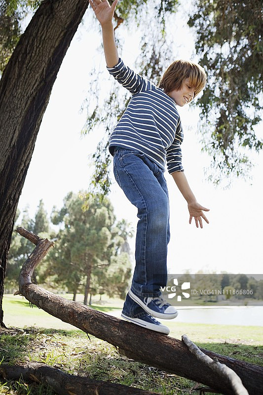 男孩在圆木上平衡图片素材