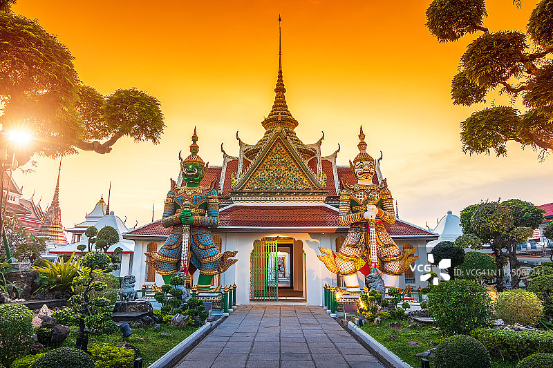 Wat Arun是一个佛教寺庙在曼谷Yai区，泰国曼谷。Wat Arun是泰国曼谷日落时著名的地标寺庙之一。阿龙寺教堂前的巨人们。图片素材