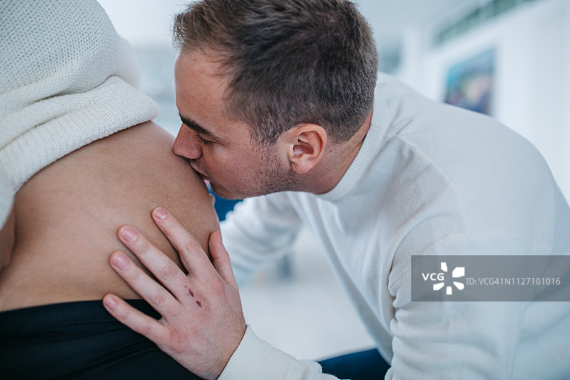 丈夫通过妻子的肚子亲吻新生儿图片素材