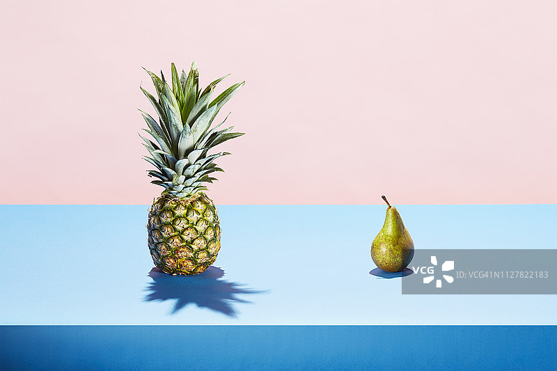 一个梨子和一个菠萝在桌面上相遇图片素材