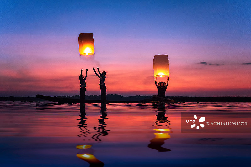 泰国湄公河上，多代同堂的一家人在夕阳下放飞天灯图片素材