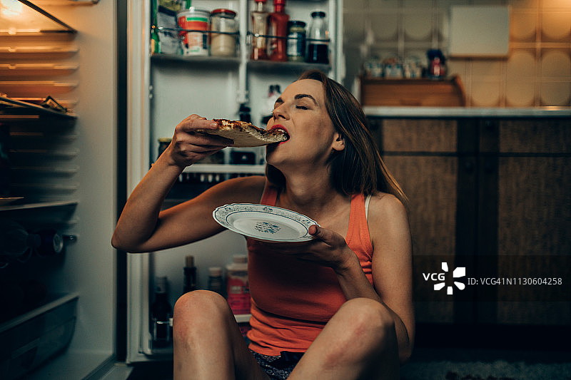在冰箱前吃披萨的女人图片素材