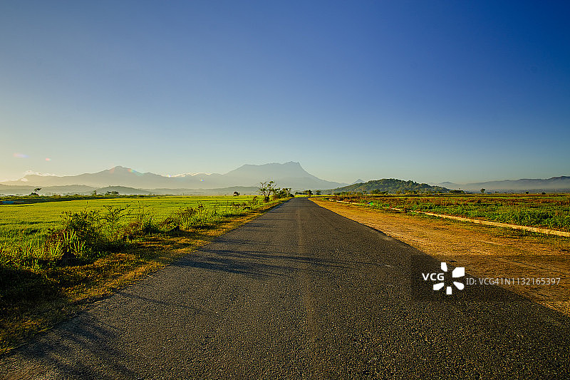 空旷的道路上的日出对基纳巴卢山和清澈的蓝天图片素材
