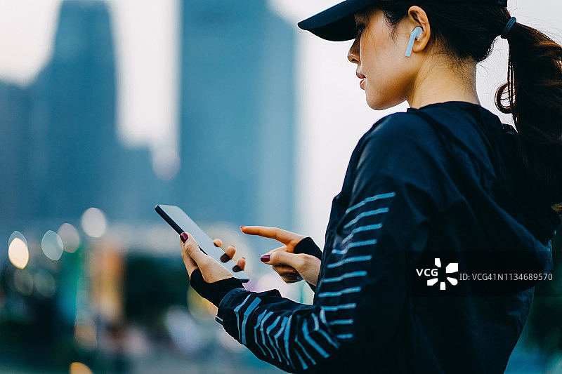 年轻的女运动员在城市锻炼后，通过智能手机应用监控自己的健身进度图片素材