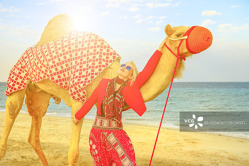 日落时牵着骆驼的女人图片素材