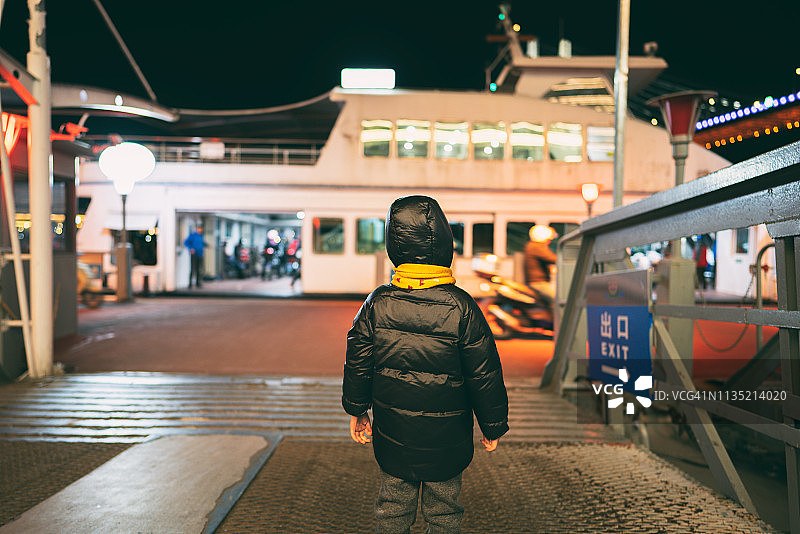 一个小男孩站在码头上看船的后视图图片素材