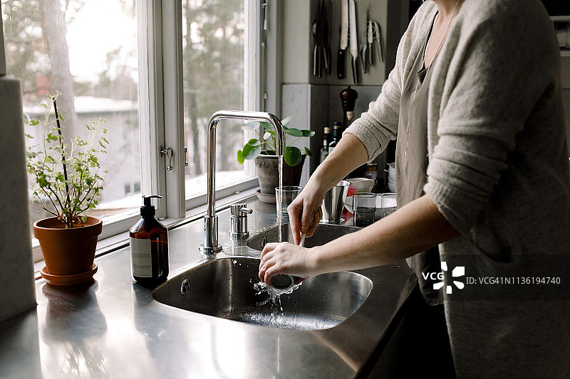 女人在家里厨房水槽里清洗杯子图片素材