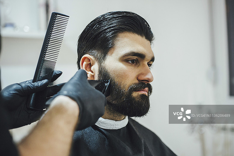 一个男人正在用电动剃须刀修剪他的胡子图片素材