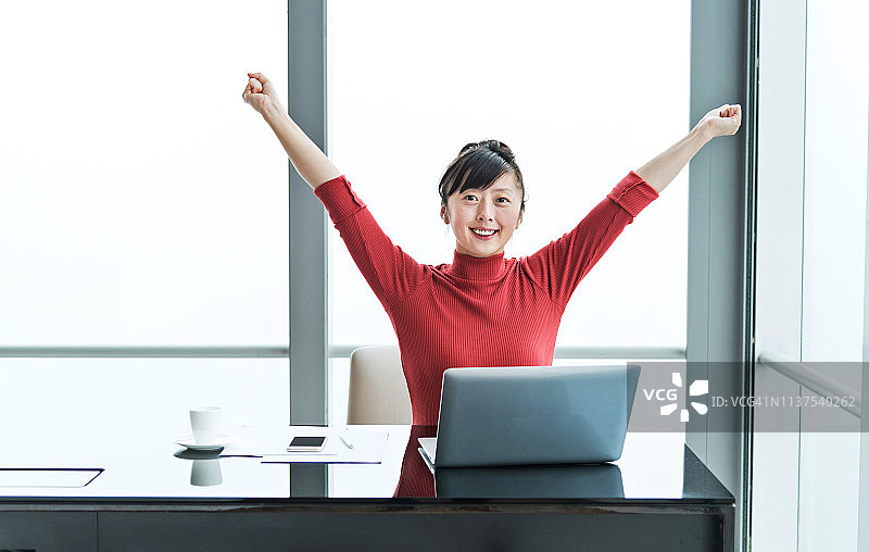 幸福的女人在办公室举起双手图片素材