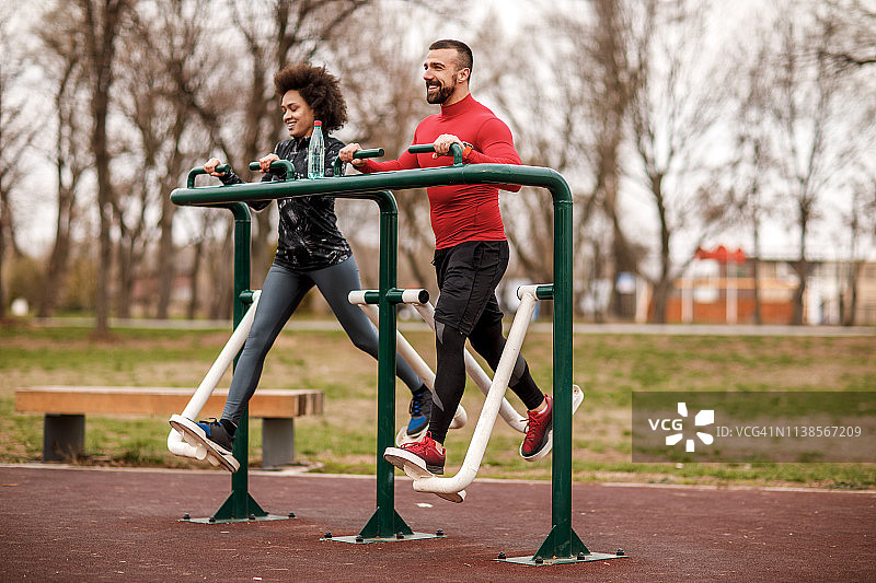 一对年轻的运动夫妇在一个公园里的步行机器上一起训练图片素材