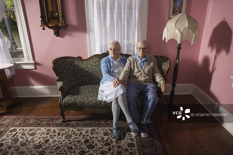亲热的老夫妇坐在客厅的沙发上图片素材
