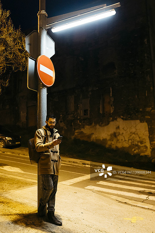 西班牙伊瓜拉达，一名男子晚上站在路灯下打手机图片素材