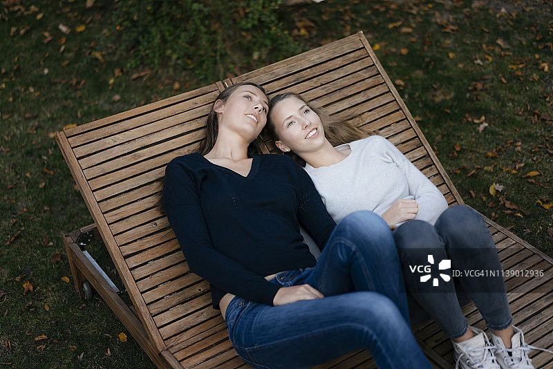 两个深情周到的少女休息在太阳躺椅上图片素材