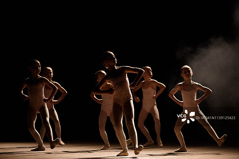 一群小型芭蕾舞者在灯光和烟雾中在舞台上排练图片素材