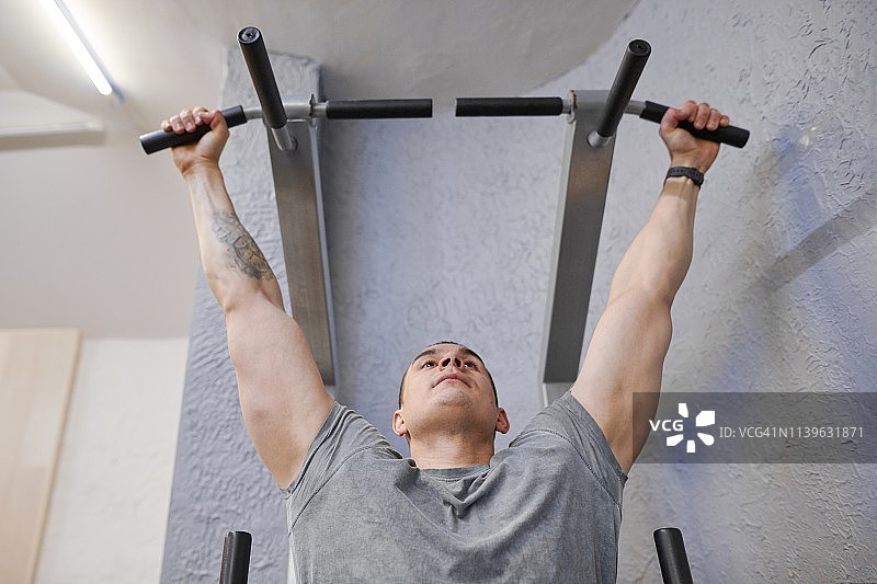 年轻强壮的男子在健身房，男性锻炼，做引体向上图片素材