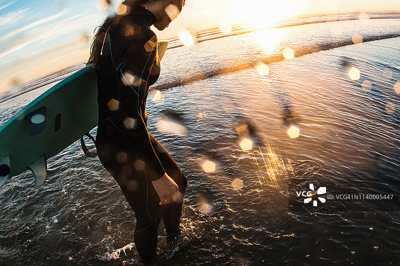 女性冲浪者在日落的海上划桨，卡迪夫-对-海，美国加利福尼亚州图片素材