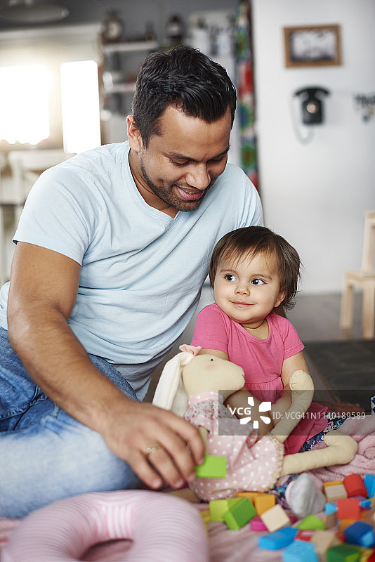 微笑的爸爸和小女孩在家里玩积木图片素材