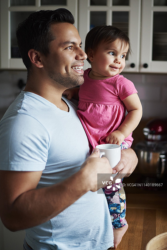 微笑的父亲抱着女儿在厨房图片素材