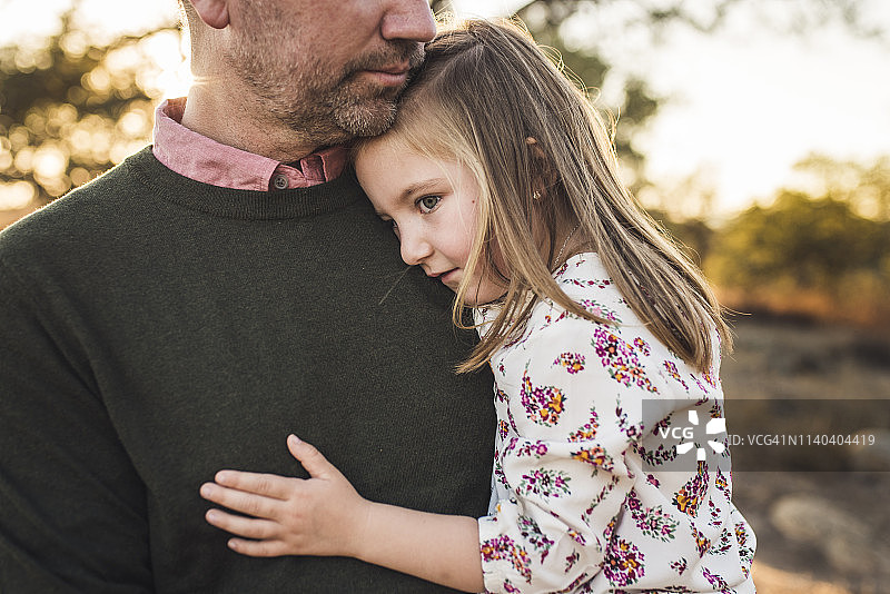 年轻女孩被父亲拥抱在加利福尼亚的田地里的特写图片素材