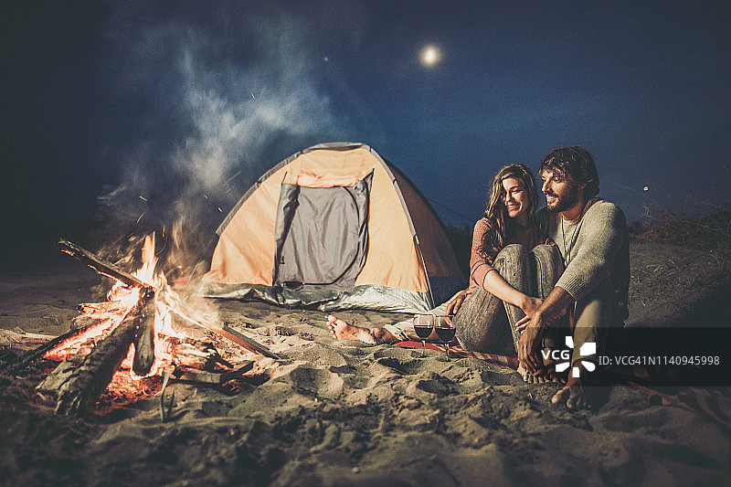 快乐轻松的夫妇享受他们的约会之夜在篝火旁。图片素材