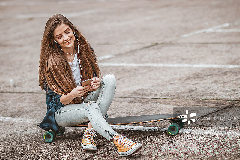 女滑板手正在街上用手机图片素材