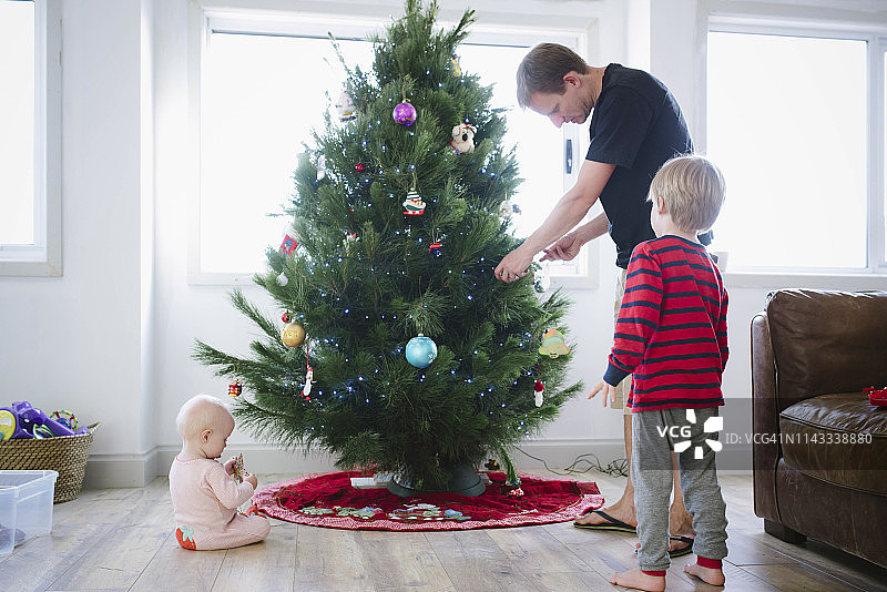父亲在家里和孩子们一起装饰圣诞树图片素材