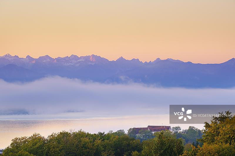德国巴伐利亚州上巴伐利亚的富恩森兰阿尔卑斯山麓，卡温德尔山脉和斯达恩堡湖在日出时，斯达恩堡城堡在前面图片素材
