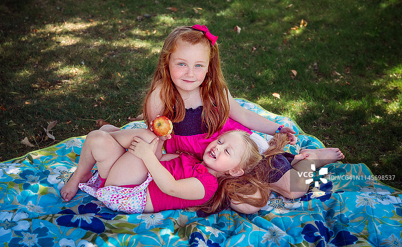姐妹们在草坪毯子上玩耍图片素材