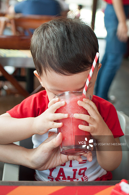 一个小男孩正在喝新鲜的水果奶昔图片素材