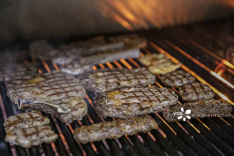 顶视图的四个烤牛肉串混合，在热的烧烤木炭烧烤和充满活力的火焰孤立在黑色背景。夏季聚会或野餐或野餐的概念。图片素材