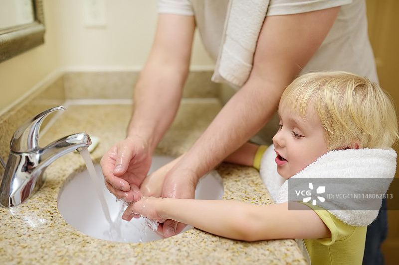 小男孩和爸爸一起在浴室里用肥皂洗手。儿童卫生。图片素材