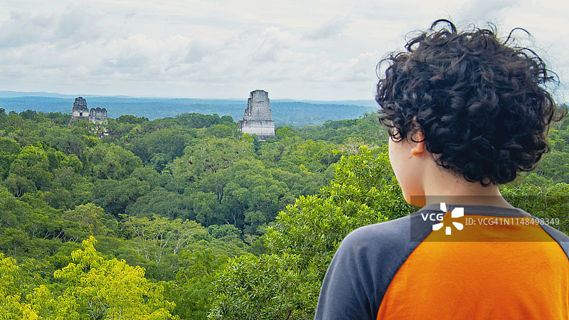 危地马拉，一名男孩在雨林和玛雅金字塔前摆姿势图片素材
