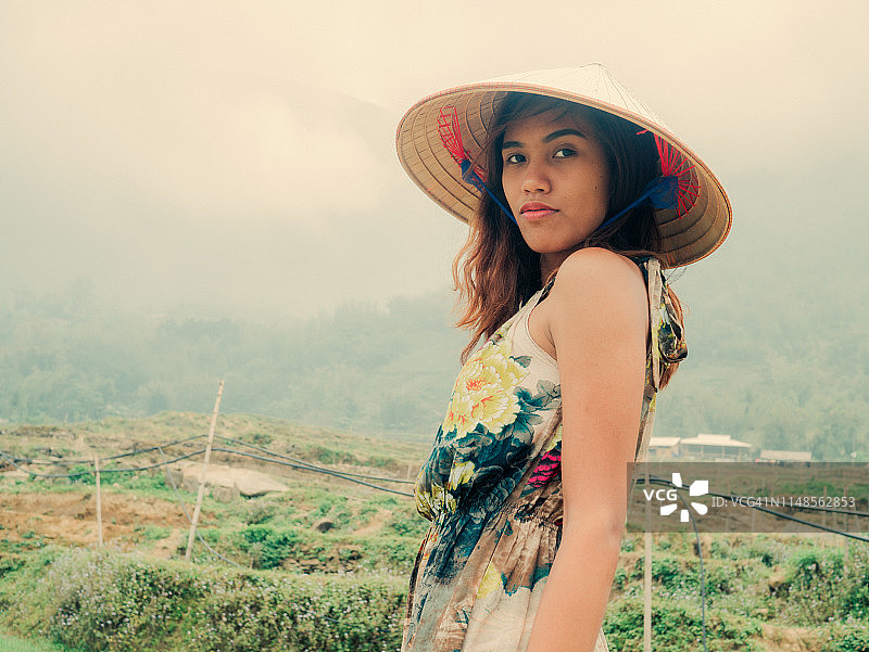 戴越南帽子的年轻女子站在稻田中图片素材