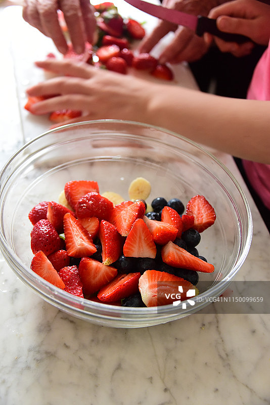 在一碗水果沙拉中加入切片的草莓图片素材