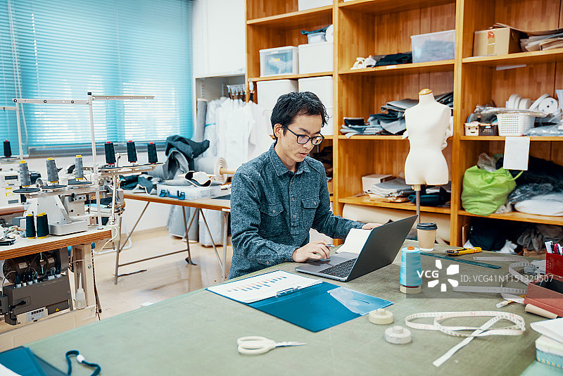 在纺织厂的电脑前工作的中年设计专业人员图片素材