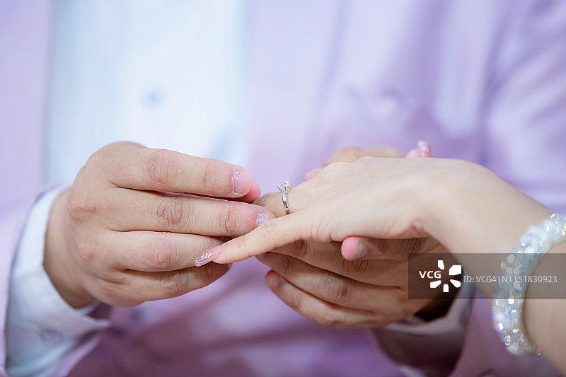 结婚戒指。他给她戴上了结婚戒指。新郎把戒指戴在新娘身上。图片素材