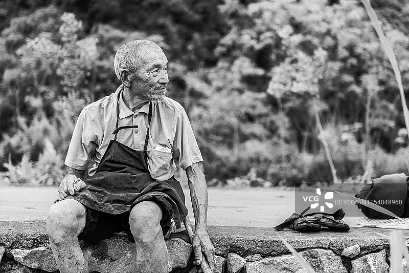 一位中国老农正坐着休息图片素材
